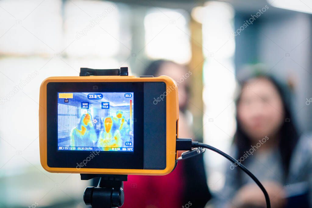 Asian people waiting for body temperature check before access to building for against epidemic flu covid19 or corona virus from wuhan in office by thermoscan or infrared thermal camera