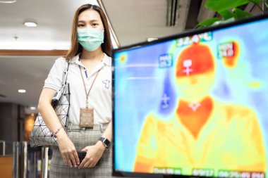 Bangkok, Tayland - 18 Mart 2020: Kimliği belirlenemeyen kişiler, vücut ısısı kontrolünün yapılmasını bekliyor.