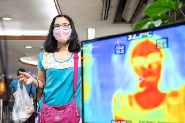 Bangkok, Tayland - 18 Mart 2020: Kimliği belirlenemeyen kişiler, vücut ısısı kontrolünün yapılmasını bekliyor.