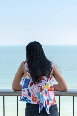 Asyalı güzel kadın deniz manzarasında rahatlıyor. Konsept seyahat, tatil, hayattaki eğlence gibi mutlu ve eğlenceli duygularla.