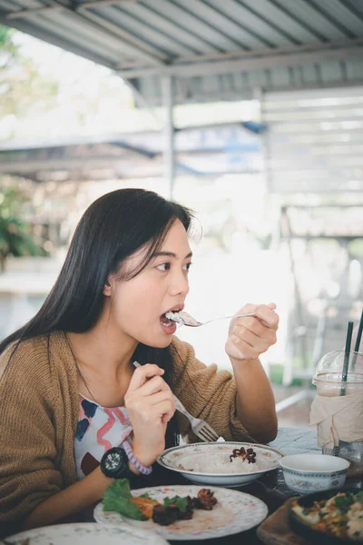 Asian pretty cute woman eating thai food with rice and many food on dining table in restaurant with happy and enjoy emotion