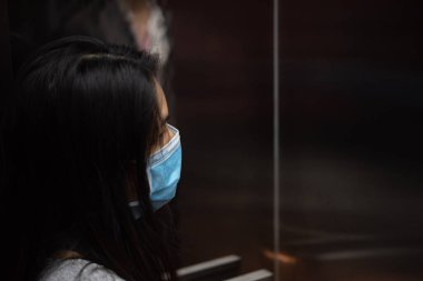 Maske takan Asyalı güzel bir kadın solunum koruma maskesi takıyor. Salgın gribe karşı. 19 yaşında ya da Wuhan 'daki Corona virüsü.
