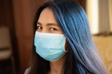Maske takan Asyalı güzel bir kadın solunum koruma maskesi takıyor. Salgın gribe karşı. 19 yaşında ya da Wuhan 'daki Corona virüsü.