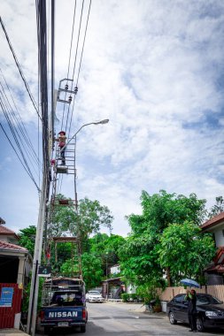 Bangkok, Tayland - 26 Haziran 2016: Tanımlanamayan elektrikçiler, tamirciler veya işçi riski Bangkok Tayland 'da kamyonet iskelesi kurarak elektrik hattını yüksek direğe kurmak için çalışma.