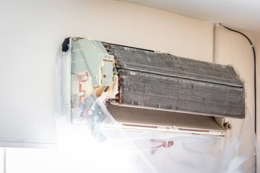 Bakım hizmeti sırasında müşteri evindeki duvardaki tozu temizlemek için havalandırma soğutucusunu suyla temizleyen işçiden işçiye.