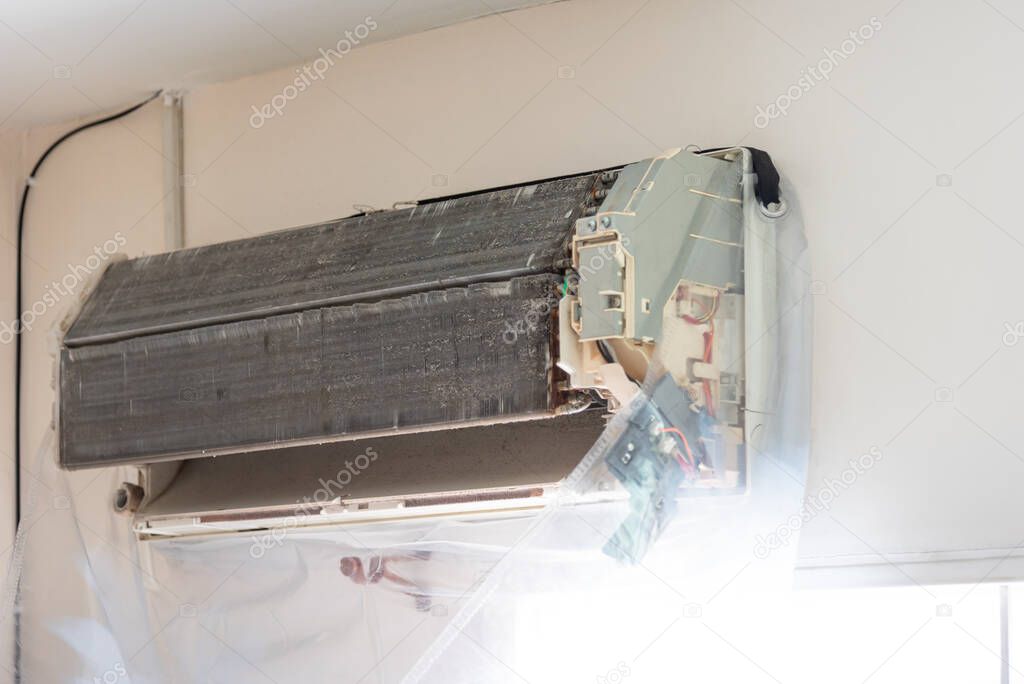 Worker to cleaning coil cooler of air conditioner by water for clean a dust on the wall in customer home when maintenance service