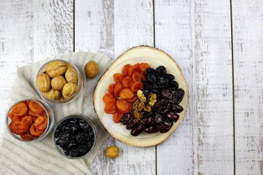 Ramazan ürünleri (iftar) tarihler, fındıklar, kurumuş kayısılar, açık ahşap arka plan görünümlü kuru erikler.
