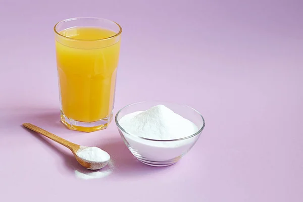 Kavanozda kolajen protein tozu, mor arka planda bir bardak portakal suyu. Cilt, kemik ve eklemler için doğal güzellik ve sağlık desteği.