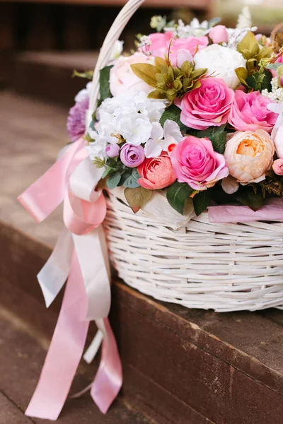 Artificial flowers in a basket. Wicker basket with ornamental flowers. Bouquet in the basket. Decorative flowers as a gift.