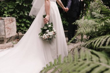 Gelin ve damat el ele tutuşuyor. Tarz sahibi damat ve gelin. Gelin ve damat için fotoğraf çekimi.. 