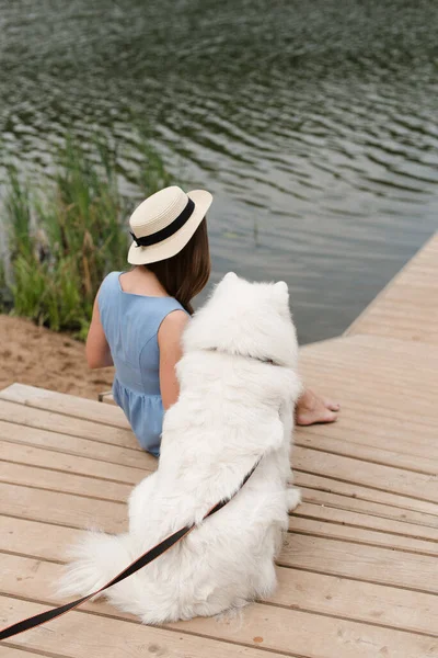 Nehir kenarında köpeği olan bir kız. Köpeği gezdiren şapkalı bir kız..