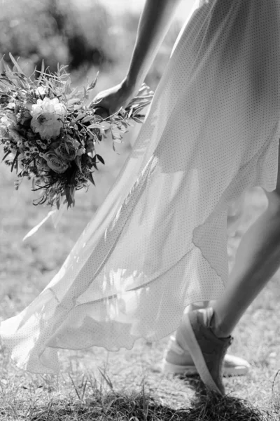 The girl is running around in a dress. Develops a dress in the wind. The girl runs with flowers. Black and white.