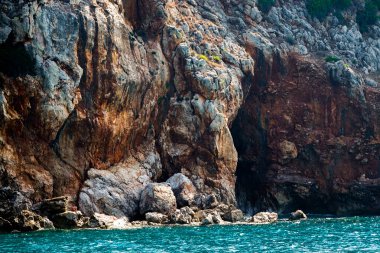 Okyanusta yeşil ağaçların bulunduğu kayalık uçurum. Kayalıkların derinliklerine uzanan bir vadi var..