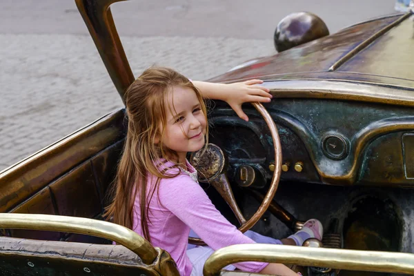 Petite fille mignonne conduisant la voiture de sculpture — Photo