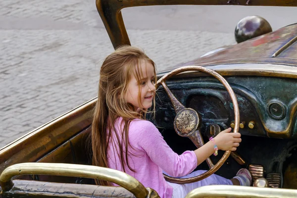 Linda niña conduciendo el coche de escultura —  Fotos de Stock