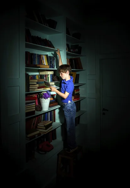 Niño pecoso de pelo rojo buscando libro en la estantería — Foto de Stock