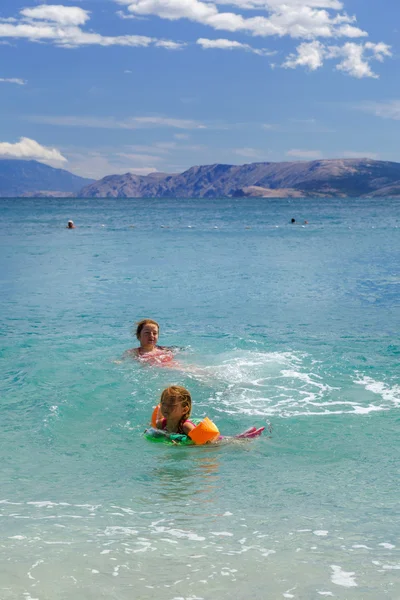 Two sisters playing games and swimming in the sea — Stock Photo, Image