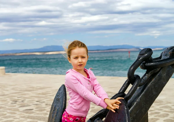 Linda niña con ancla de barco en la playa — Foto de Stock