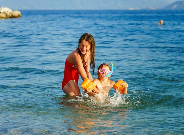 Two sisters playing games and swimming in the sea — Stock Photo, Image