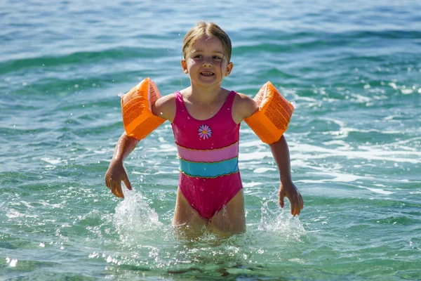 Nettes kleines Mädchen schwimmt im Meer mit Wasserflügel — Stockfoto