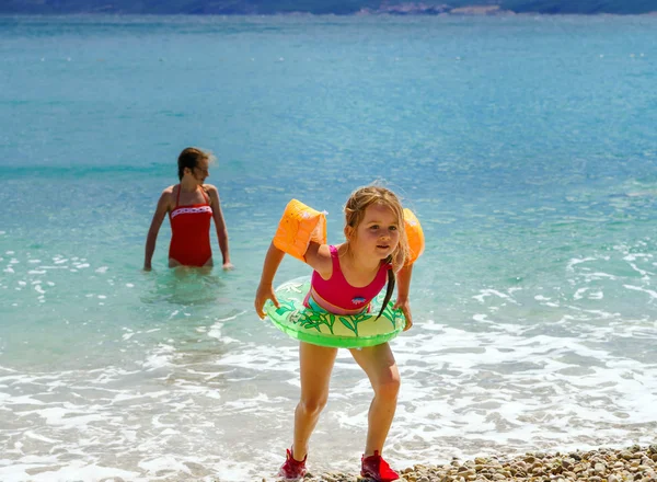 Two sisters playing games and swimming in the sea — Stock Photo, Image