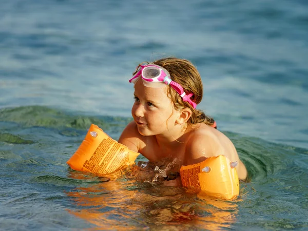 Cute little girl swimming in the sea with water wing — Stock Photo, Image