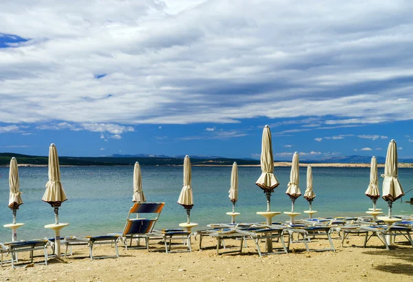 Playa de mar vacía con sombrillas cerradas, Croacia, terreno tormentoso — Foto de Stock