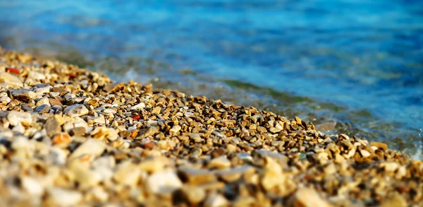Pequeñas piedras en la playa cerca del agua —  Fotos de Stock