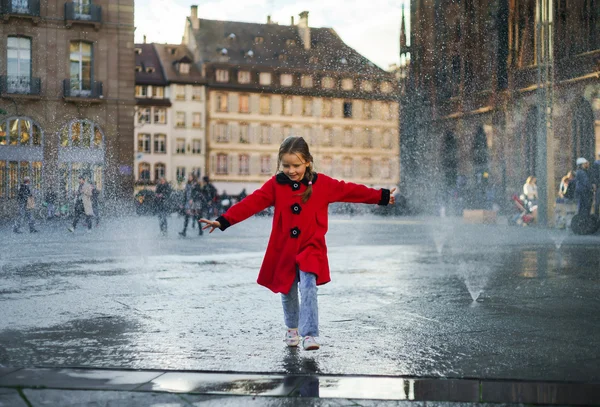 Cute little girl playing in water splash of street fountain — Stock Photo, Image