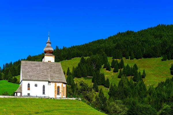 Güzel küçük kilise Alpleri'nde. Güneşli bir gün, yeşil çimenlerin üzerinde h — Stok fotoğraf