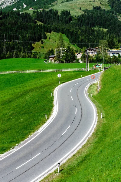 Estrada rural alpina em campos verdes — Fotografia de Stock