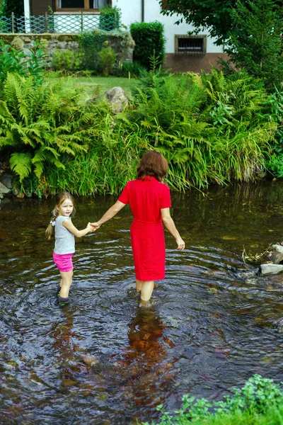 Mother with daughter crossing little river — Stock Photo, Image