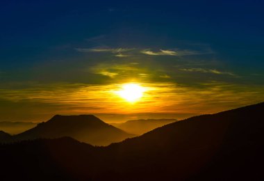 Dağlar ve canlı siluetleri ile pastoral günbatımı manzara