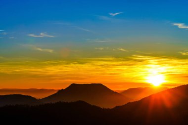 Dağlar ve canlı siluetleri ile pastoral günbatımı manzara