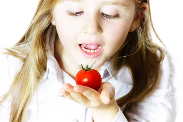 Liten flicka visar små röda tomat — Stockfoto