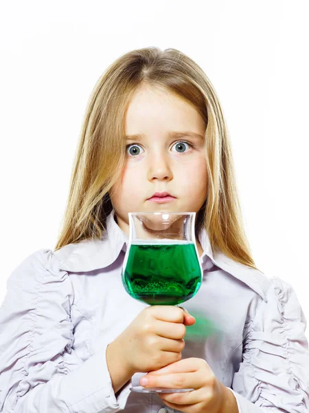 Petite fille avec un verre de liquide vert vif, peut-être du poison — Photo