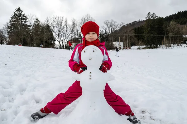 Lilla flickan att göra snögubbe vinterdag — Stockfoto