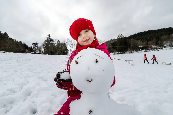 Lilla flickan att göra snögubbe vinterdag — Stockfoto