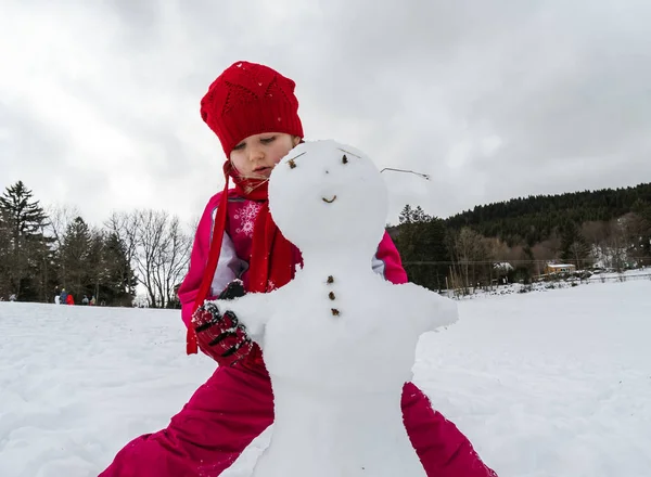 Lilla flickan att göra snögubbe vinterdag — Stockfoto