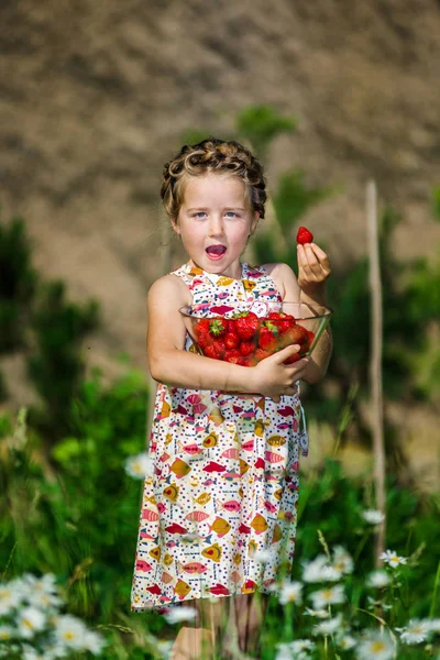 Cute little girl posing with fresh red strawberry in the sunny g — Stock Photo, Image