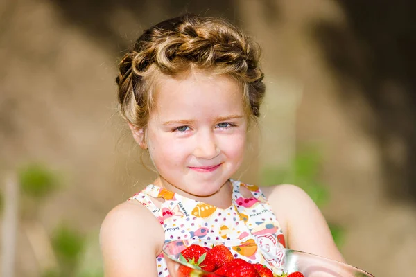 Niedliche kleine Mädchen posiert mit frischen roten Erdbeeren in der sonnigen g — Stockfoto