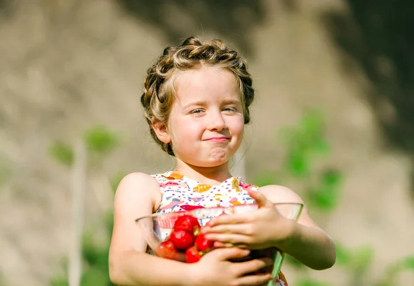 Gadis kecil yang manis berpose dengan stroberi merah segar di cerah g — Stok Foto