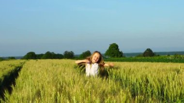 Buğday alanı güneşli bir günde, yavaş hareket görünümü oynayan sevimli küçük kız