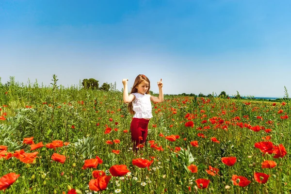 Söt liten flicka som leker i röd vallmo fält sommar dag, skönhet — Stockfoto