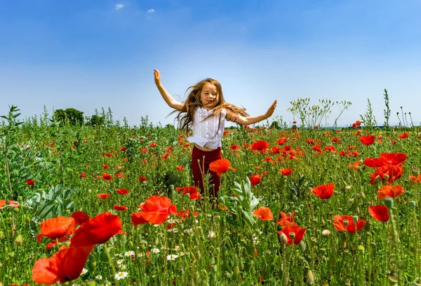 Söt liten flicka som leker i röd vallmo fält sommar dag, skönhet — Stockfoto