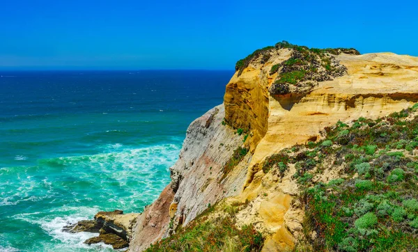 Gele rotsen en zand op de Portugese kust, levendige oceaanwater — Stockfoto