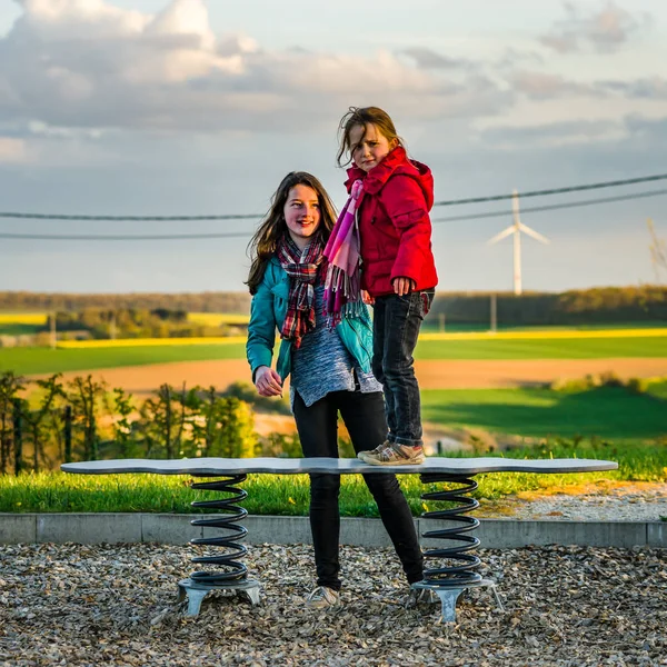 Deux sœurs : maternelle et adolescente - jouer sur une aire de jeux — Photo