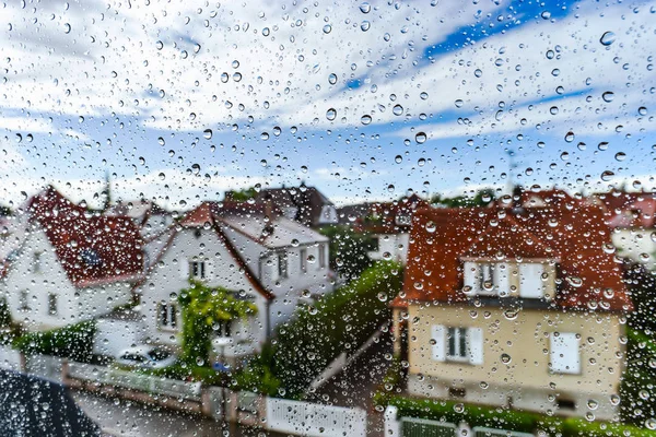 Regenwetter-Blick durch das Fenster mit Wassertropfen auf dem Dach — Stockfoto