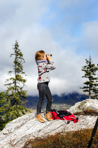 Linda niña investigando montañas de los Alpes usando binocular. T — Foto de Stock