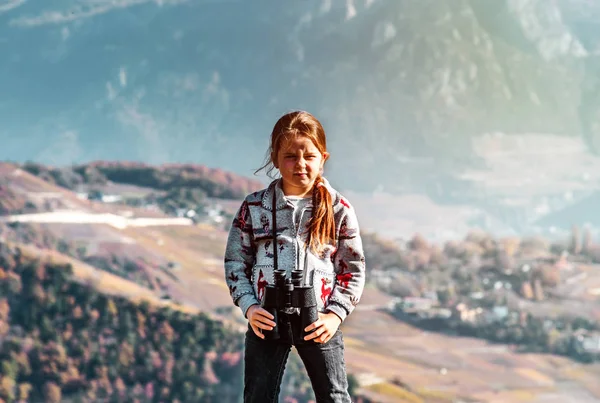 Aranyos kislány Alpok hegyek távcső segítségével vizsgálja. T — Stock Fotó